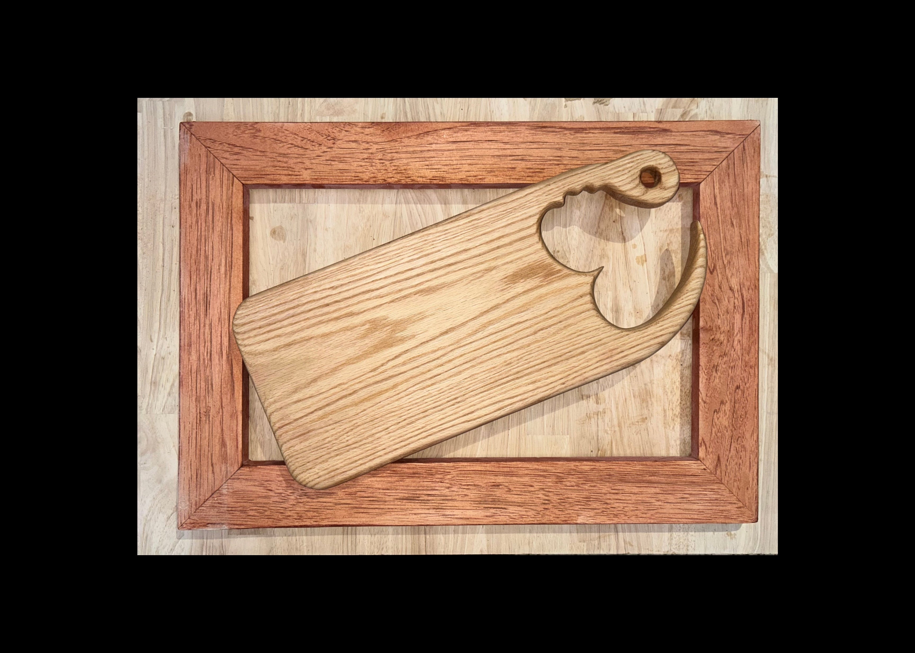 White Oak chopping block with heart-shaped cut-out for the handle, in a wooden frame on a light wood background